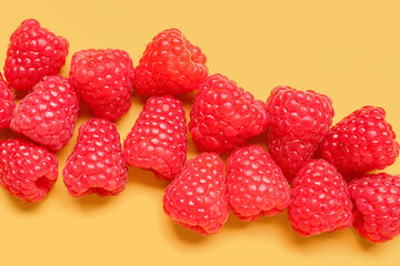 Many fresh raspberries on yellow background