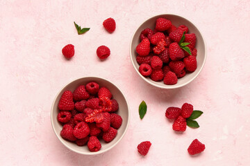 Bowl with fresh raspberries and mint on pink background