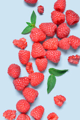 Many fresh raspberries and mint on blue background