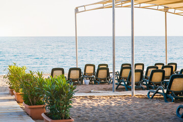 empty sandy beach with sun loungers and a canopy, beautiful blue calm sea