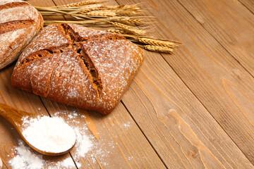 Loaf of fresh rye bread and wheat flour on wooden table