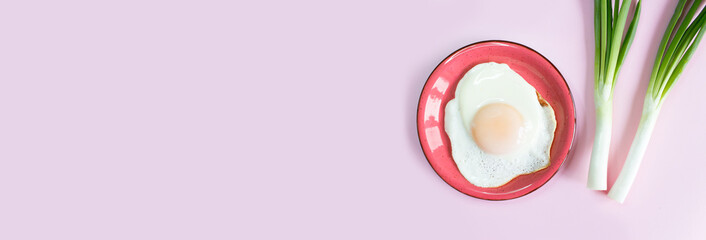 Sunny side up egg banner. Fried eggs with green onions on a pink background