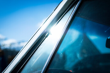 Sunlight shining on a chrome frame of a windshield of an old vintage car close up still