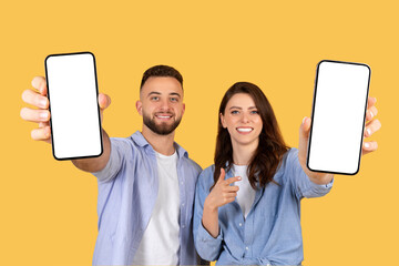Cheerful couple holding smartphones with blank screens, ideal for mockups