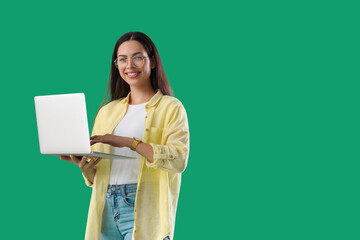 Pretty young female programmer with laptop on green background