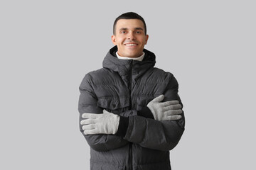 Young man in warm puffer jacket on light background © Pixel-Shot