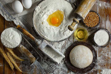 The process of kneading dough in the kitchen. Eggs, flour and other ingredients on the kitchen table in a composition.