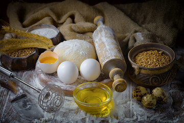 The process of kneading dough in the kitchen. Eggs, flour and other ingredients on the kitchen table in a composition.