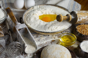 The process of kneading dough in the kitchen. Eggs, flour and other ingredients on the kitchen table in a composition.