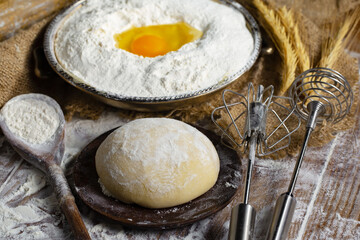 Kneading dough with flour and eggs, on an old background
