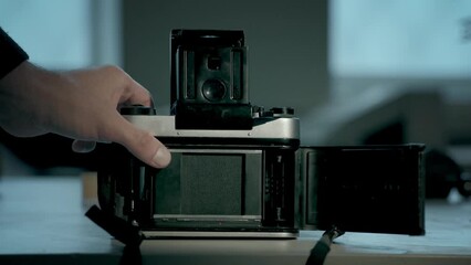 A vintage film camera on the table in the workshop. Master is checking shutter operation. Slowmotion, footage 4K. 