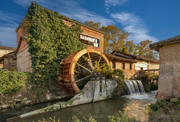 Old disused paddle mill with rusted iron wheel near a canal in the Po Valley in Piedmont, Italy