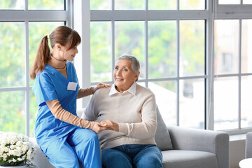 Senior woman with caregiver holding hands at home