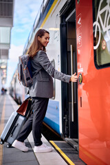 Happy woman getting into train at station.