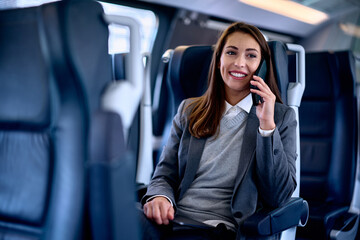 Happy female entrepreneur talking on cell phone while commuting by train.