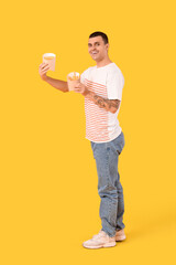 Happy young man with french fries on yellow background