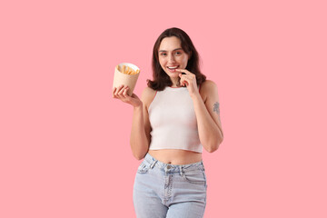 Young woman with french fries on pink background