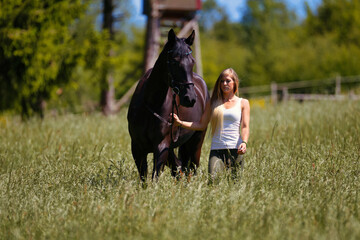 Naklejka na ściany i meble Woman young blonde long hair on a meadow in summer with horse.