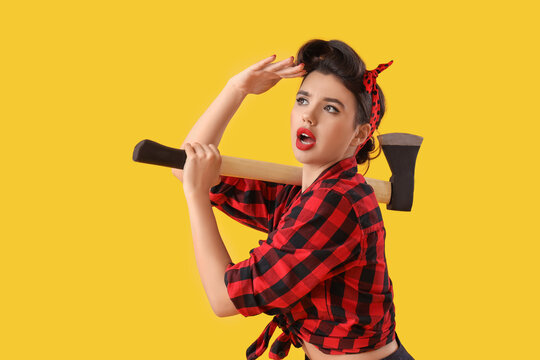 Young pin-up woman with axe looking away on yellow background