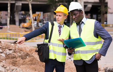 African-american and European men engineers discussing road repairing works. One engineer pointing...