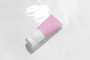 Pink and white mockup tube of cream in water with reflection on white isolated background. Concept of cosmetic beauty products, face and body care.