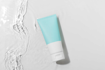 Blue and white mockup tube of cream in waves of water on white isolated background. Concept of natural beauty products for skin hydration, face and body care cosmetics