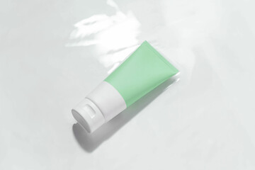 Green and white mockup tube of cream in water with reflection on white isolated background. Concept of cosmetic beauty products, face and body care.