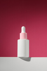 On a pink background a bottle with serum stands on a platform. Vertical advertising photo of cosmetics. Mockup. Template.