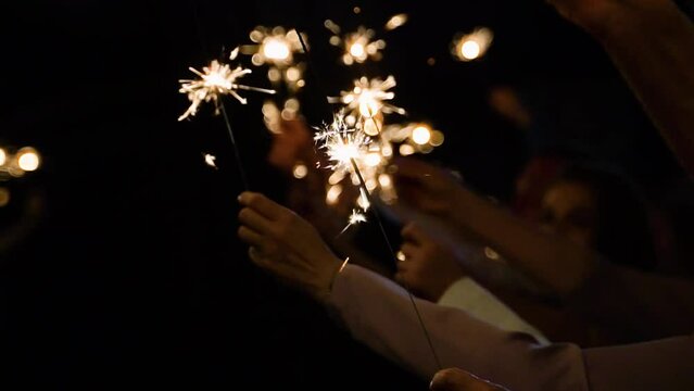 A crowd of young happy people with sparklers in their hands during celebration