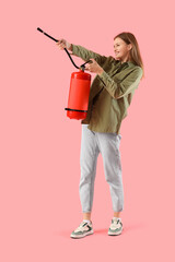 Young woman with fire extinguisher on pink background