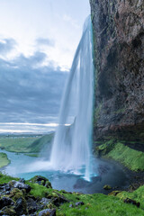 Masses of water cascade from the Seljalandsfoss waterfall down into a big lake.