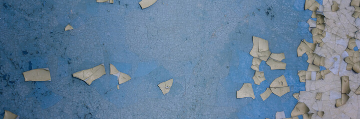 Peeling paint on the wall. Panorama of a concrete wall with old cracked flaking paint. Weathered rough painted surface with patterns of cracks and peeling. Wide panoramic grungy texture for background