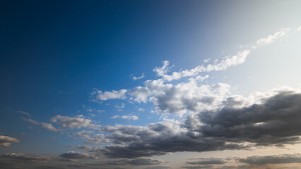 beautiful blue sky with dark dramatic cumulus clouds and sunlight for abstract background