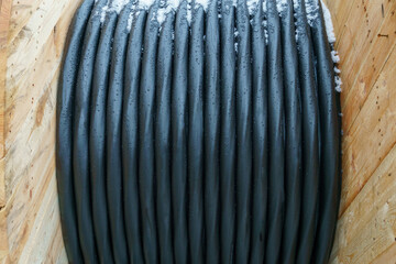 An electric cable in a polymer winding on a wooden coil. A high-voltage cable located on a construction site. Close-up of the cable bay. Optical fiber for the Internet.
