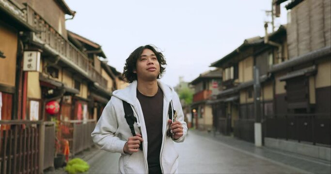 Man, Japan and travel or city street with backpack or adventure, vacation or cultural history. Asian person, walk and street or urban buildings for education as tourist or holiday, weekend or trip