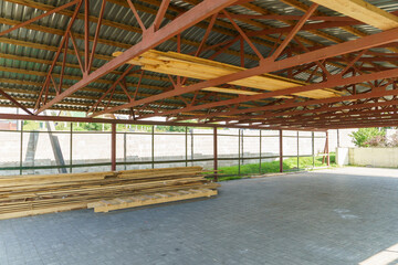 A large ventilated warehouse with a metal roof for storing and drying boards and wooden products. Logging, furniture manufacturing.