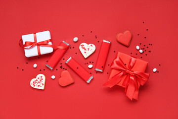 Tasty chocolate bars with heart-shaped cookies and gift boxes on red background. Valentine's Day celebration