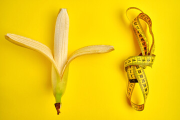 Measuring tape and banana on yellow background. Weight loss concept. Men's health concept. Top...