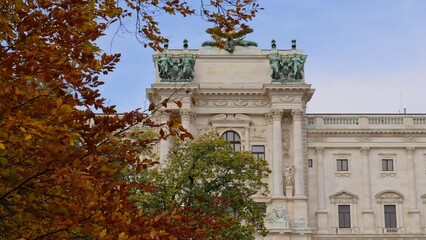 Facade of Neue Burg, part of Hofburg Palace, revealed by leaves on a colorful autumn tree in Burggarten Park, Vienna, Austria