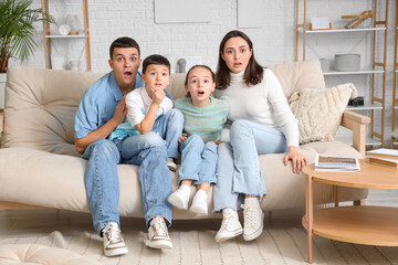 Shocked family watching TV on sofa at home