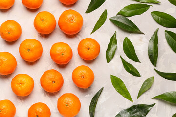 Sweet mandarins and leaves on grey background