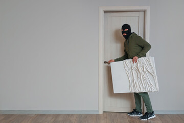 Male thief stealing painting at door in room