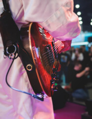 Concert view of an electric guitar player with vocalist and rock band performing in a club, male...