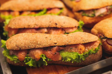 Beautifully decorated catering banquet table with different food snacks and appetizers setting with sandwiches, bagels, baguette club submarine sandwich, on wooden plate, on party or celebration