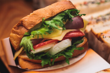 Beautifully decorated catering banquet table with different food snacks and appetizers setting with sandwiches, bagels, baguette club submarine sandwich, on wooden plate, on party or celebration