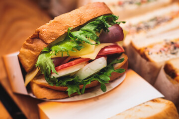 Beautifully decorated catering banquet table with different food snacks and appetizers setting with sandwiches, bagels, baguette club submarine sandwich, on wooden plate, on party or celebration