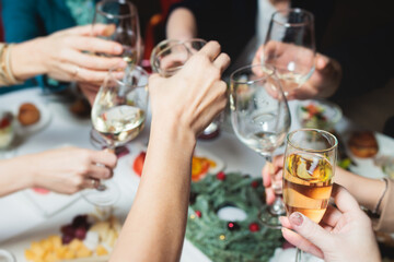Group of guests celebrate and raise glasses, toasting and cheering with alcohol glasses with wine and champagne in the restaurant on corporate christmas birthday party event or wedding celebration