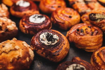 Pastry, selection assortment variety of different bakery, with cinnamon bun, croissant, swiss rolls, cake, eclair and others in a basket or a plate, baked desserts, catering or cafe banquet table