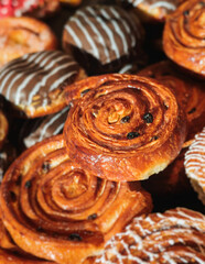 Pastry, selection assortment variety of different bakery, with cinnamon bun, croissant, swiss rolls, cake, eclair and others in a basket or a plate, baked desserts, catering or cafe banquet table