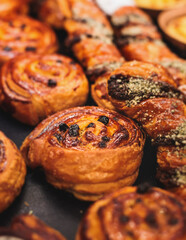 Pastry, selection assortment variety of different bakery, with cinnamon bun, croissant, swiss rolls, cake, eclair and others in a basket or a plate, baked desserts, catering or cafe banquet table